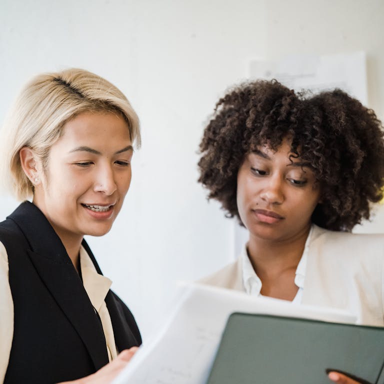 Two women engaging in a business meeting, reviewing documents and collaborating on a project.